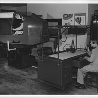 A black and white photograph of two men training on the simulator