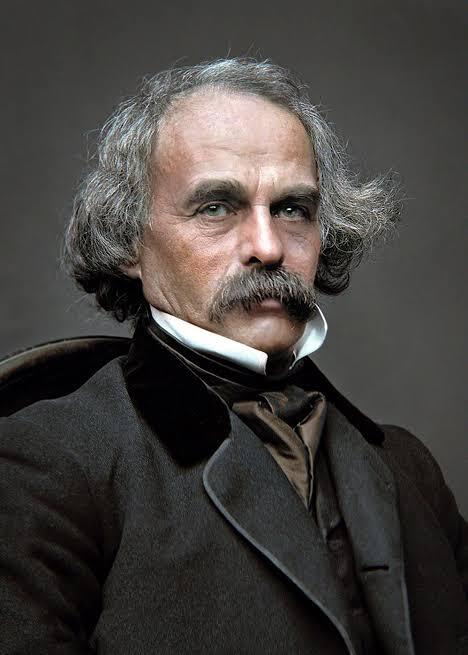 This picture of Nathaniel Hawthorne shows him wearing a black suite. He has grey hair and a grey mustache. He is looking at the camera with a blank stare. 