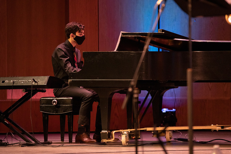 Band member Elias wearing a mask playing on the piano on stage