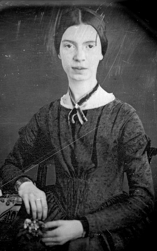 This black and white image of Emily Dickinson shows her wearing a black dress with a thin black scarf. She has her hair tied in the back and is looking at the viewer with a blank face. 