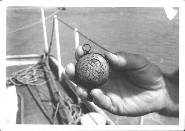 A black and white photograph of a hand holding an antique pocket watch