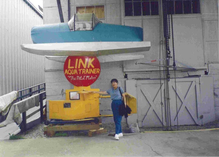A colored photograph of a woman standing next to the last Link Aqua Trainer