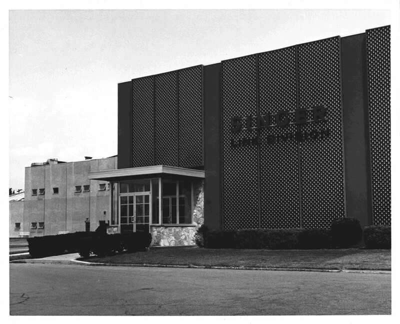 A black and white photograph of a factory building with the words Singer Link Division across the front