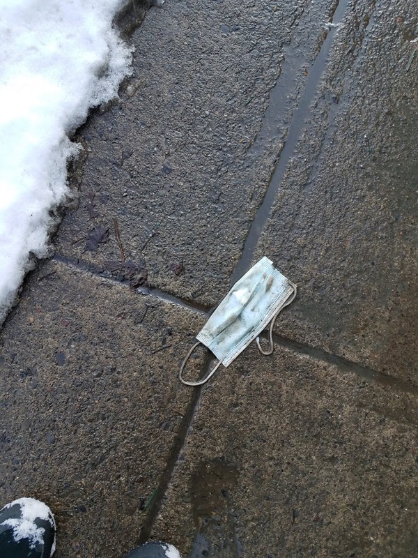 Discarded surgical mask on wet snowy concrete