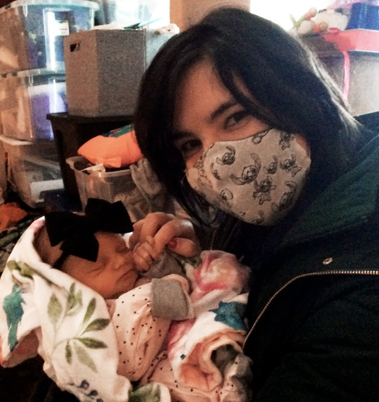 Angela with her mask on, and her cute little baby niece, holding onto her finger