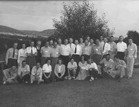 A black and white photograph of men and women facing the camera and posing for a group picture