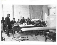 A black and white photo of a man doing a demonstration while several other men watch