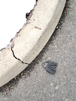 Discarded black surgical mask on the side of the curb