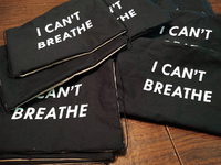 Scattered pile of fabric masks with white text "I CAN'T BREATHE"