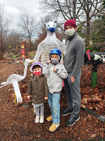 Asian guy wearing a mask standing with a little boy and girl, both also masked, posing in front of the masked wire polar bear sculpture at The Story Garden