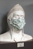 A large white marble sculpture of Dante wearing the light green floral side of a fabric mask