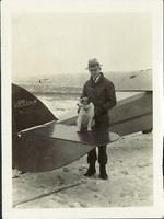 A black and white photograph of a man with a dog standing next to an airplane