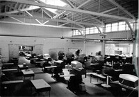 A black and white photograph of the Link Aviation factory floor with rows of trainers