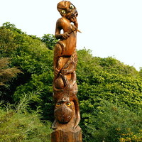 The image shows a large wooden carving that represents the Māori legend of Kupe and Te Wheke. An octopus-like figure can be seen wrapped around towards the bottom of the structure, with another figure towards the top, holding a sort of tool or weapon. 
