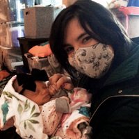 Angela with her mask on, and her cute little baby niece, holding onto her finger