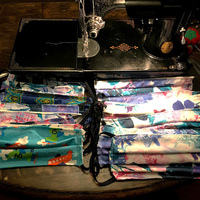 Piles of fabric masks laid out in front of a black vintage sewing machine